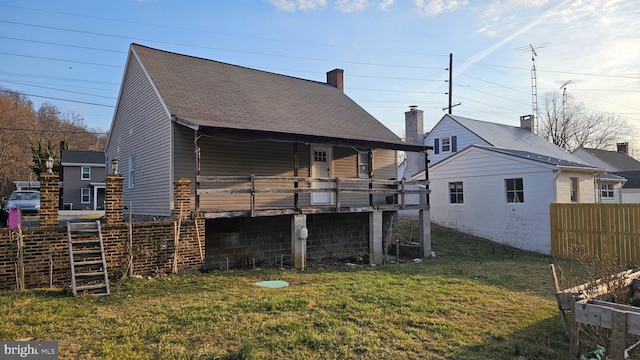 back of property with a lawn, fence, and roof with shingles