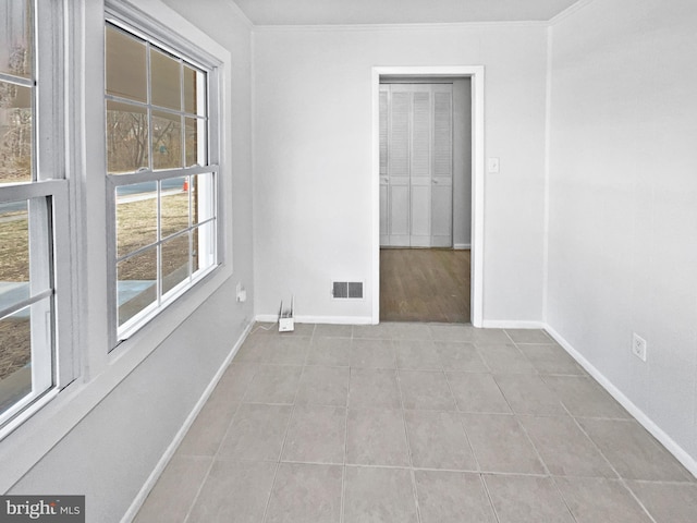 spare room with visible vents, baseboards, ornamental molding, and tile patterned flooring