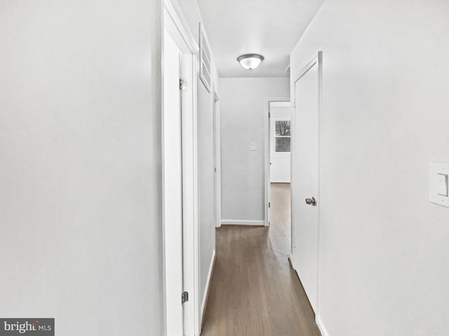 corridor featuring baseboards and wood finished floors