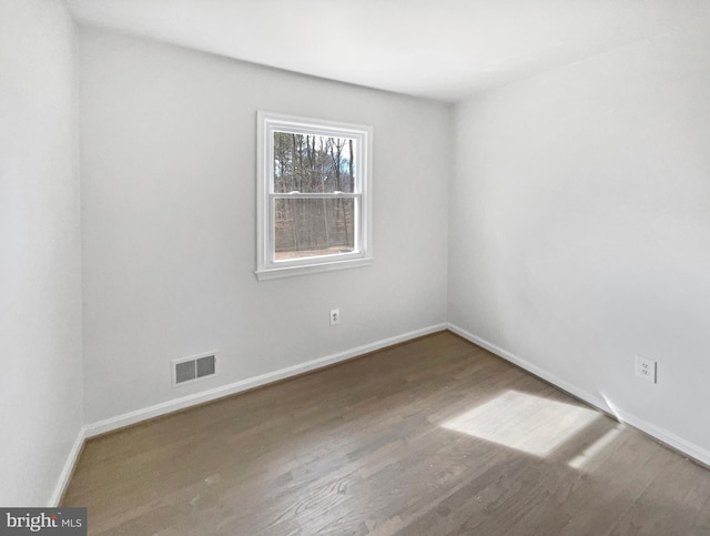 unfurnished room featuring visible vents, baseboards, and wood finished floors