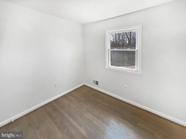 spare room with wood finished floors, baseboards, and visible vents