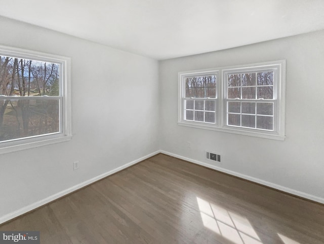 spare room featuring visible vents, baseboards, and wood finished floors