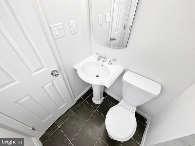 bathroom featuring tile patterned flooring, toilet, and baseboards