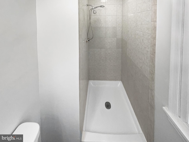 full bathroom featuring toilet and tiled shower