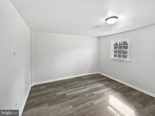 spare room featuring visible vents, baseboards, and dark wood-style flooring