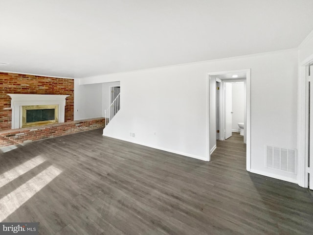 unfurnished living room with visible vents, a brick fireplace, dark wood-type flooring, baseboards, and stairs