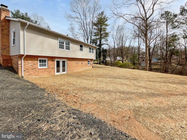 back of property with brick siding, driveway, and a chimney