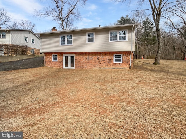 back of property featuring brick siding, french doors, and a chimney