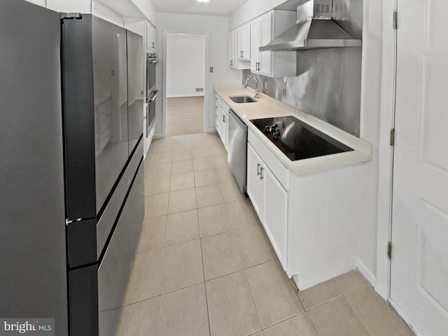 kitchen featuring light tile patterned floors, a sink, white cabinets, appliances with stainless steel finishes, and wall chimney range hood