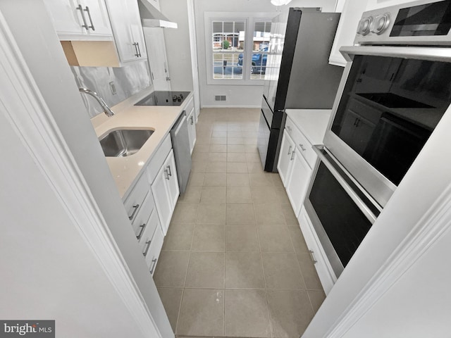 kitchen featuring under cabinet range hood, a sink, appliances with stainless steel finishes, white cabinets, and light tile patterned floors