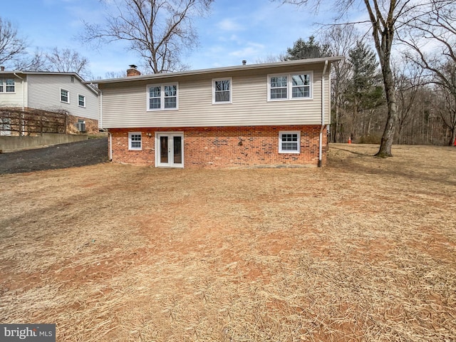 back of property featuring french doors, brick siding, and a chimney