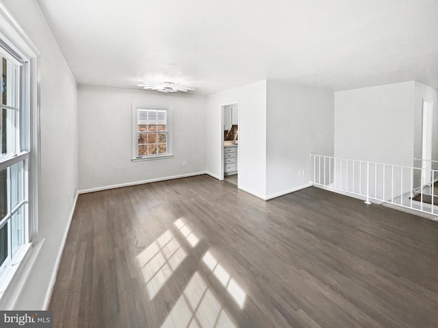 spare room featuring baseboards and dark wood-style flooring