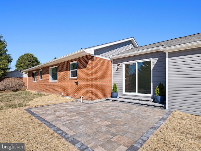 rear view of property featuring a patio and brick siding