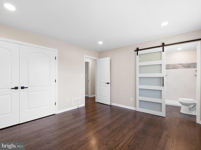 unfurnished bedroom featuring visible vents, a barn door, recessed lighting, wood finished floors, and a closet