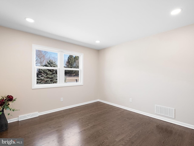 spare room with baseboards, visible vents, and dark wood-style flooring