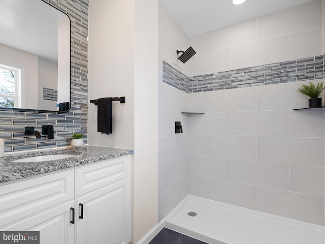 bathroom with backsplash, vanity, and a tile shower