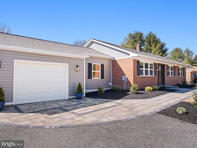 ranch-style house featuring brick siding, an attached garage, decorative driveway, and roof with shingles