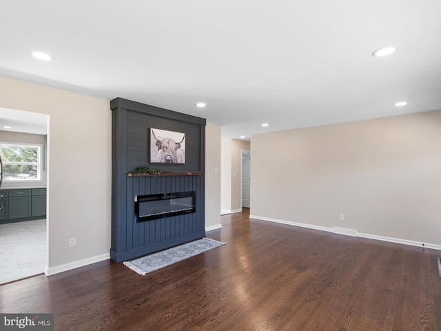 unfurnished living room featuring visible vents, baseboards, recessed lighting, a fireplace, and dark wood-style floors