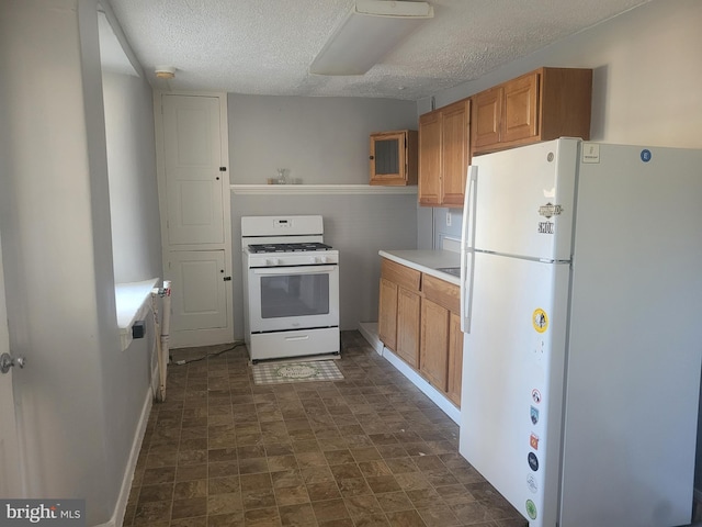 kitchen featuring white appliances, light countertops, baseboards, and a textured ceiling