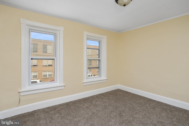 carpeted spare room with baseboards, plenty of natural light, and crown molding