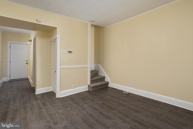 unfurnished room featuring baseboards, dark wood finished floors, stairs, and crown molding