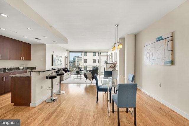 dining area with floor to ceiling windows, recessed lighting, light wood-style flooring, and baseboards