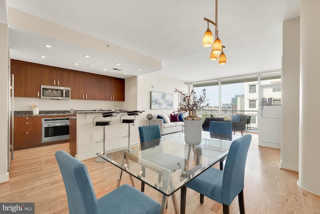 dining area with recessed lighting, baseboards, a wall of windows, and light wood-style floors