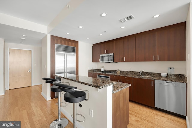 kitchen with visible vents, light wood-type flooring, a breakfast bar, a sink, and appliances with stainless steel finishes