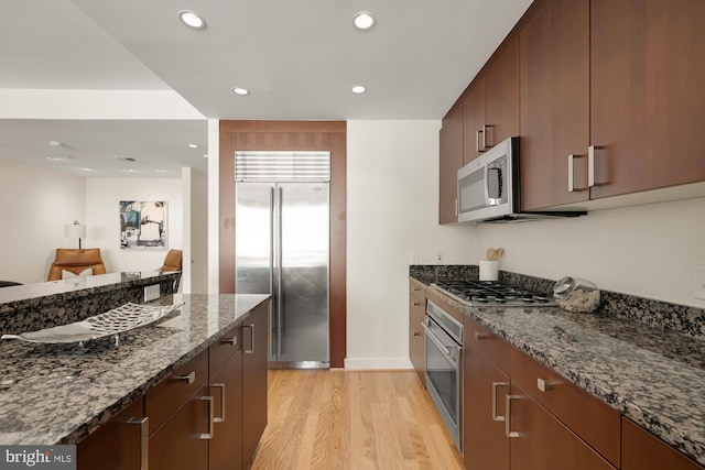 kitchen featuring dark stone counters, recessed lighting, light wood finished floors, and stainless steel appliances