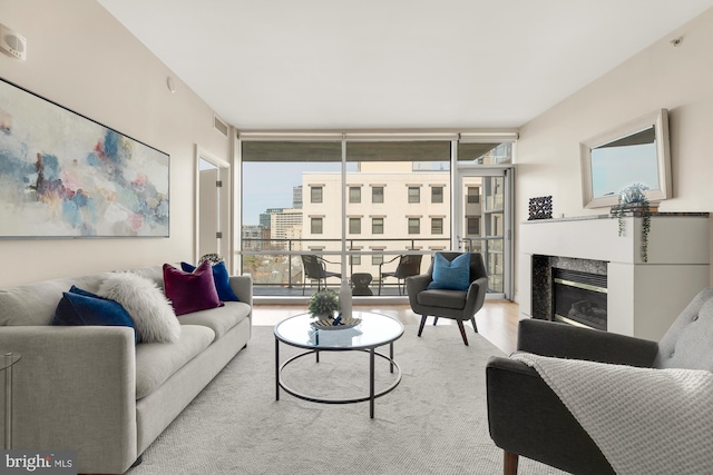 living area with a wealth of natural light, a premium fireplace, wood finished floors, and expansive windows