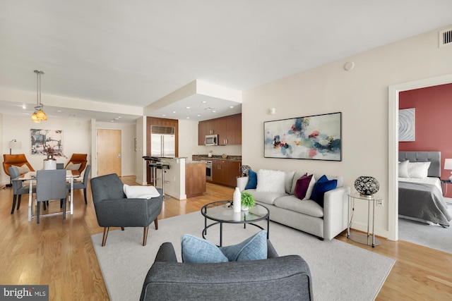 living area with light wood finished floors, visible vents, recessed lighting, and baseboards