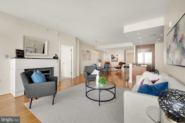 living room with visible vents, a high end fireplace, recessed lighting, light wood-style floors, and baseboards