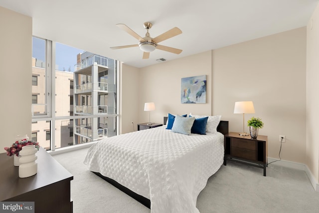 bedroom with visible vents, baseboards, a wall of windows, carpet flooring, and a ceiling fan