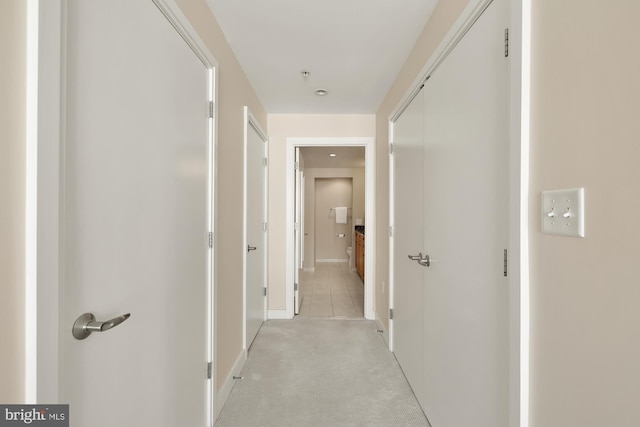 hallway with baseboards and light carpet