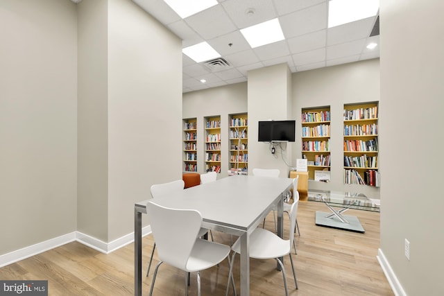 dining room with visible vents, a drop ceiling, baseboards, and wood finished floors