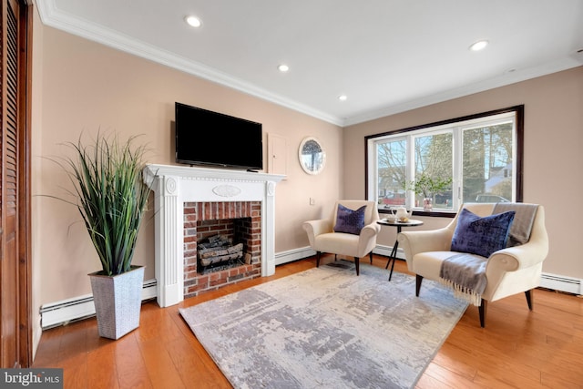 sitting room featuring a baseboard heating unit, a brick fireplace, and crown molding