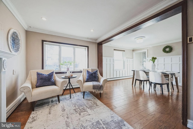 sitting room with baseboard heating, wood finished floors, and ornamental molding