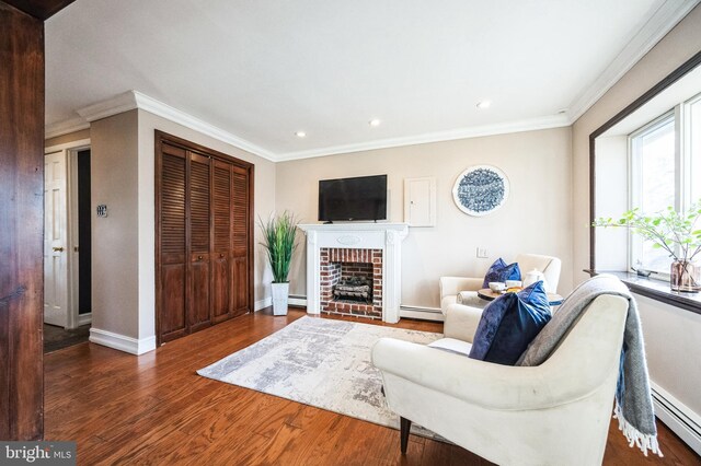 living room featuring crown molding, a baseboard heating unit, baseboards, and wood finished floors