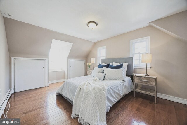 bedroom featuring a baseboard heating unit, wood-type flooring, baseboards, and vaulted ceiling