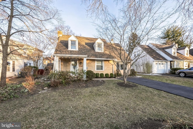 cape cod-style house with aphalt driveway, a front yard, roof with shingles, and a chimney