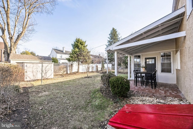 view of yard featuring a patio, a storage unit, fence, and an outdoor structure