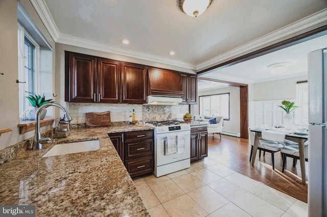 kitchen with a sink, light stone counters, white appliances, decorative backsplash, and dark brown cabinets