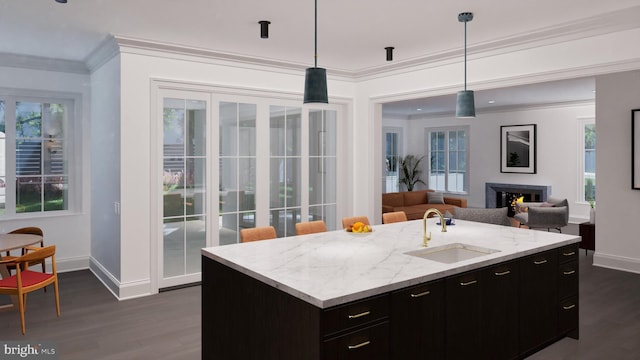 kitchen with baseboards, dark wood finished floors, ornamental molding, a warm lit fireplace, and a sink