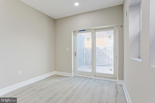 spare room with baseboards, wood finished floors, and recessed lighting