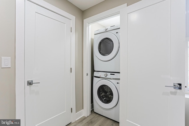washroom with stacked washer and dryer, laundry area, and light wood finished floors