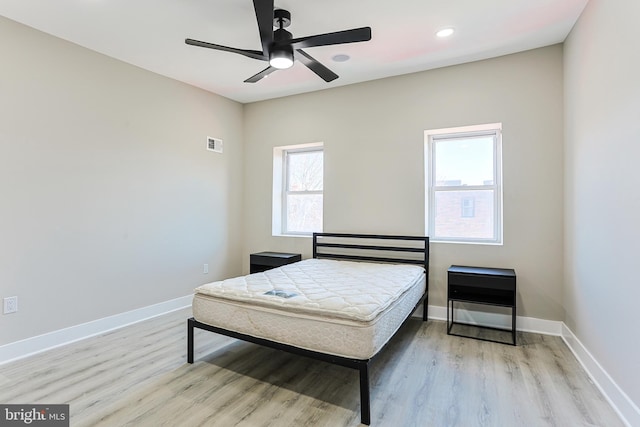 bedroom with baseboards, visible vents, and wood finished floors