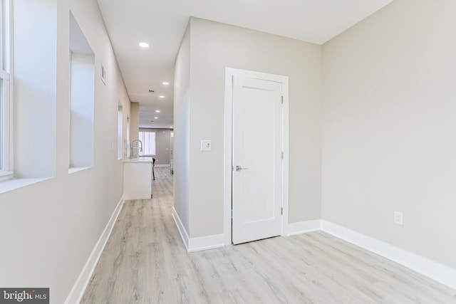 hallway featuring recessed lighting, baseboards, a sink, visible vents, and wood finished floors