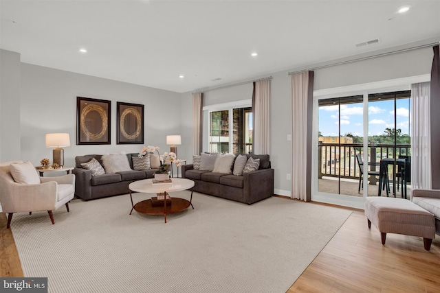 living area with recessed lighting, visible vents, plenty of natural light, and light wood-style flooring