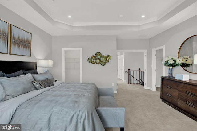 bedroom featuring light carpet, a tray ceiling, recessed lighting, a closet, and a spacious closet