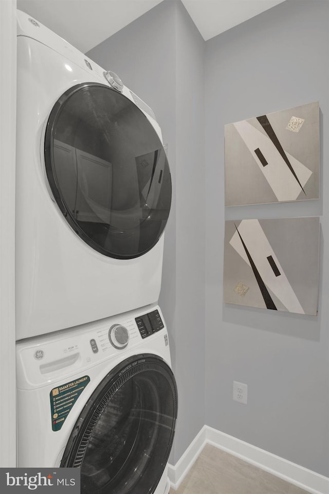 laundry room featuring laundry area, baseboards, and stacked washer and dryer